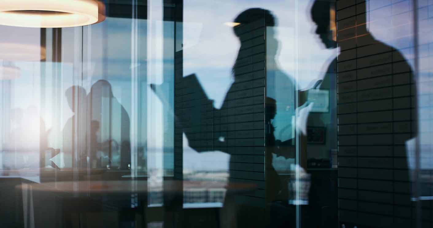 Silhouettes of a group of business people standing or walking in the office building