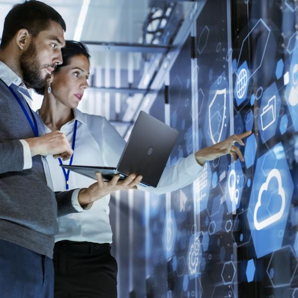 Two people looking at a big screen with information technology 